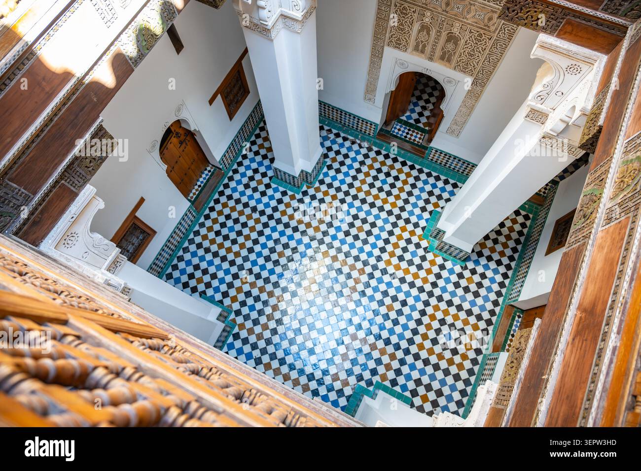 L'intérieur de la Madrasa Ben Youssef montre des chambres d'étudiants avec des carreaux colorés et un mobilier simple. Banque D'Images