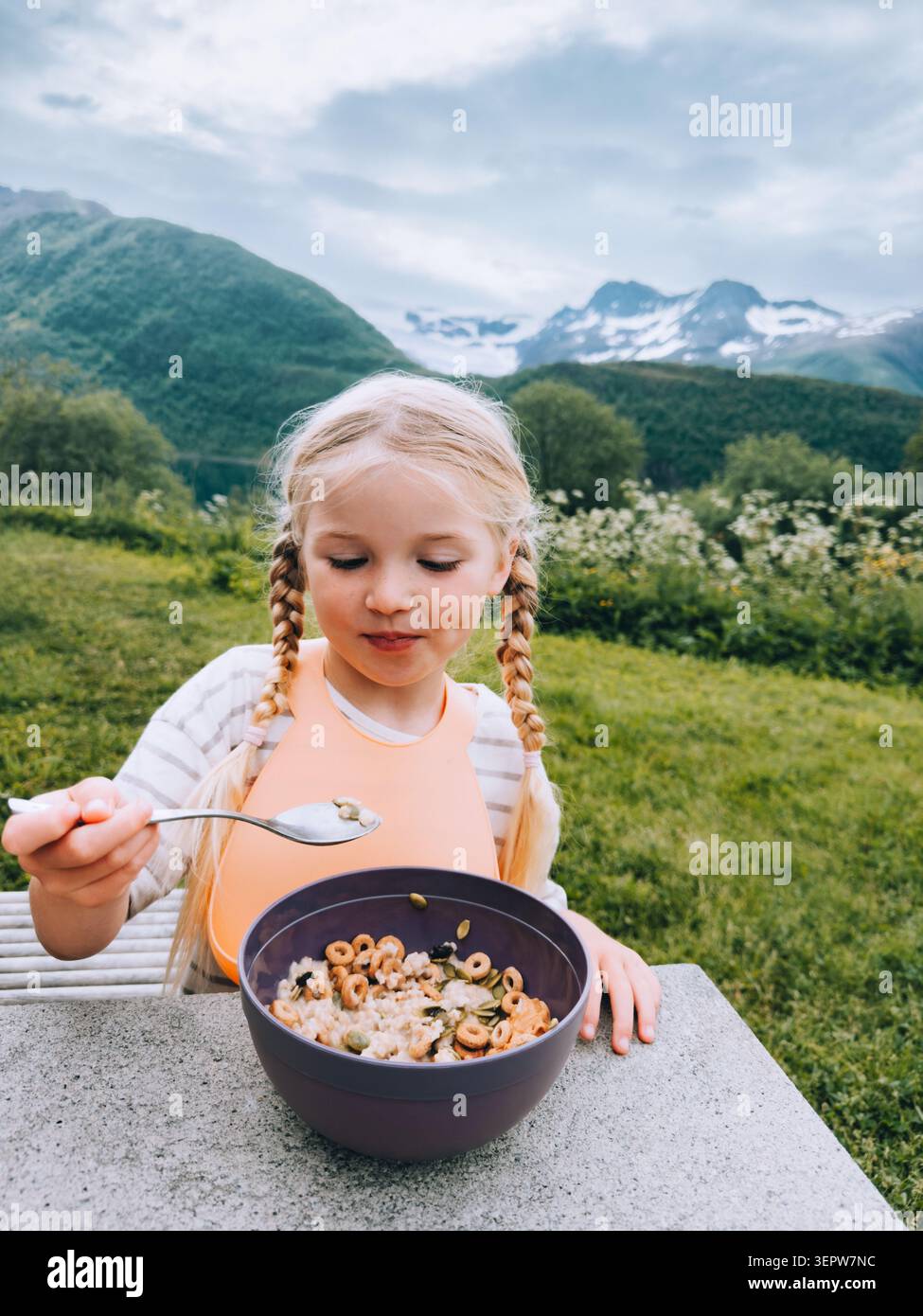 Enfant fille mangeant le petit déjeuner granola pique-nique d'été voyage en plein air vacances camping en Norvège, mode de vie sain végétalien nourriture saine 5 ans enfant esprit Banque D'Images