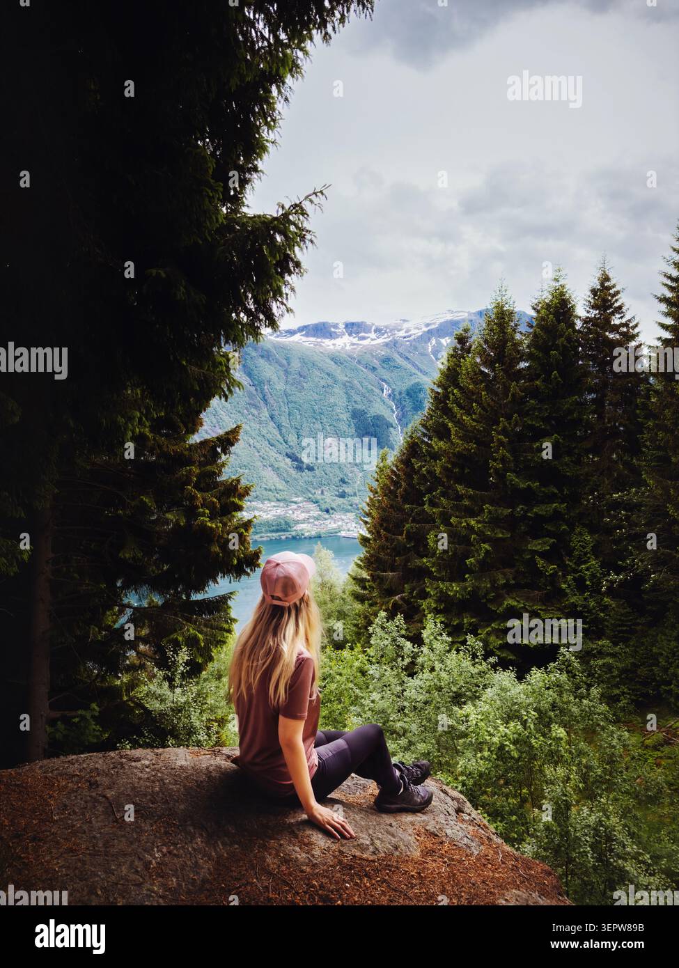 Femme voyageuse appréciant la forêt et la vue sur le fjord assis sur la falaise seule en Norvège, fille touriste voyage solo en plein air aventure de style de vie sain actif su Banque D'Images