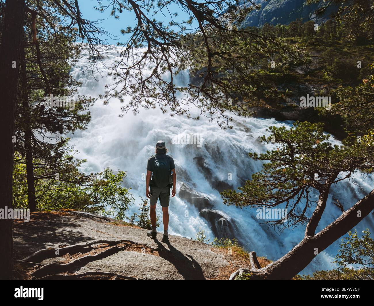 Homme Backpacker voyage solo en Norvège randonneur touriste appréciant la vue sur la cascade dans la vallée de Husedalen, voyageur sur les vacances d'été explorer Hardangervidda PA Banque D'Images