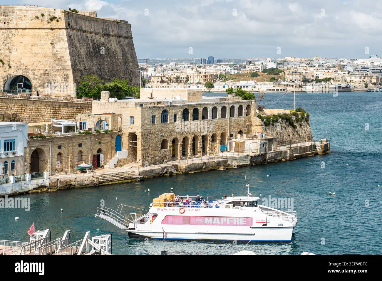 La Valette, Malte – 16 mai 2025 : ferry de passagers opérant entre Sliema et la Valette navigue le long du front de mer historique, entouré de calcaire Banque D'Images