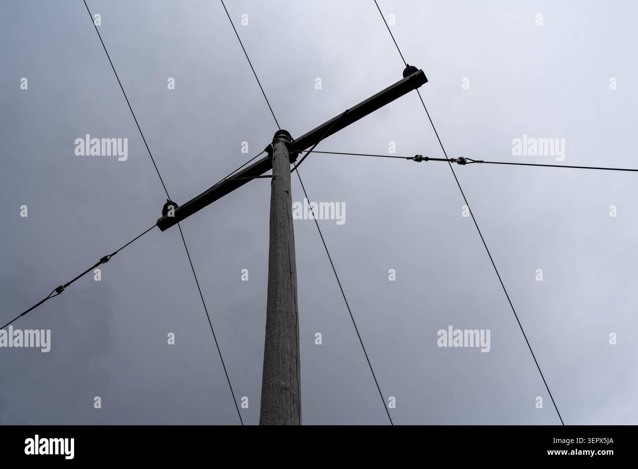 Poteau électrique et lignes aériennes contre un ciel nuageux Banque D'Images