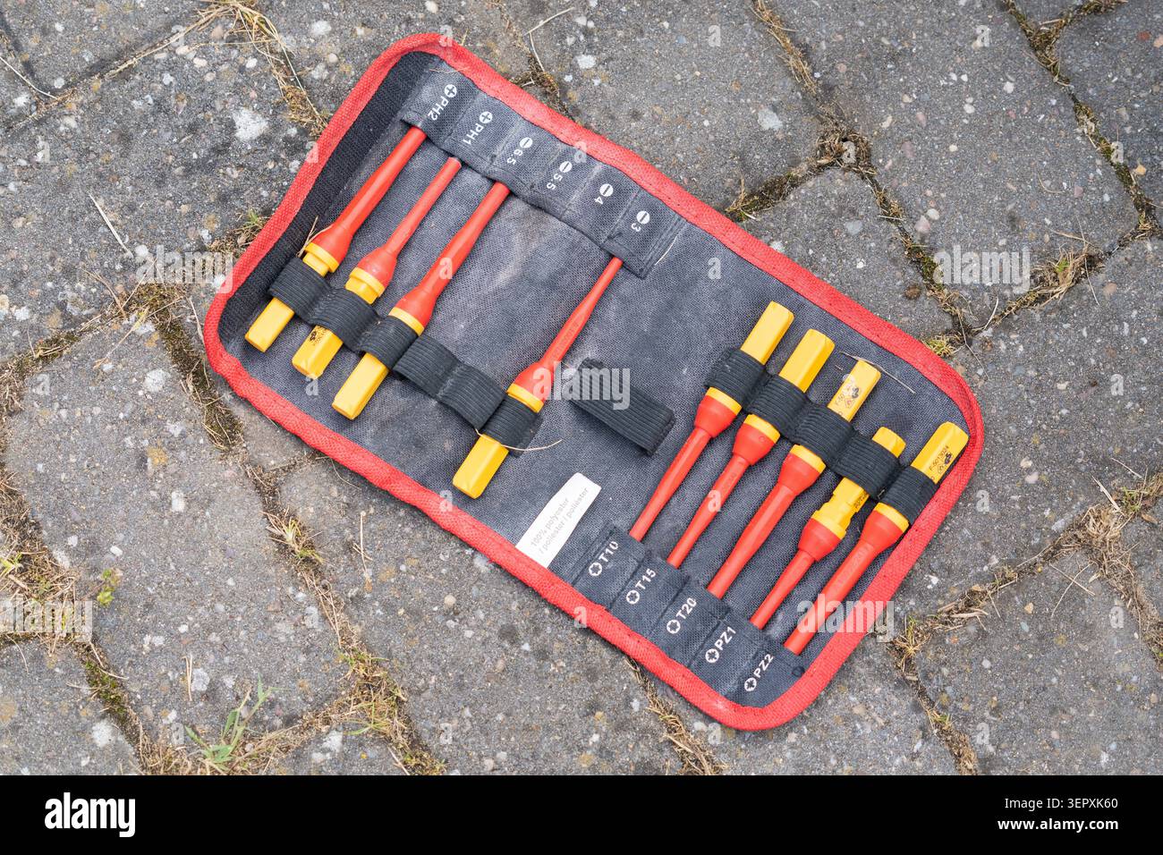 Jeu de tournevis d'électricien isolé dans un rouleau d'outils en tissu sur des pierres de pavage Banque D'Images