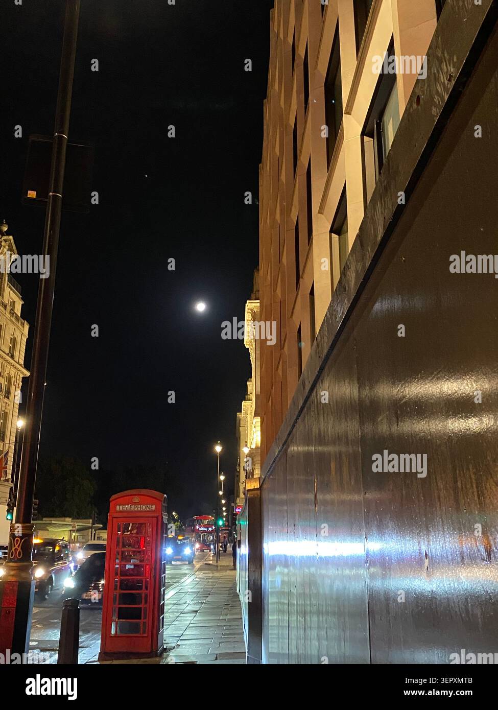 Cabine téléphonique rouge traditionnelle illuminée la nuit à Mayfair, Londres, Angleterre. - Image de stock capturée avec un smartphone