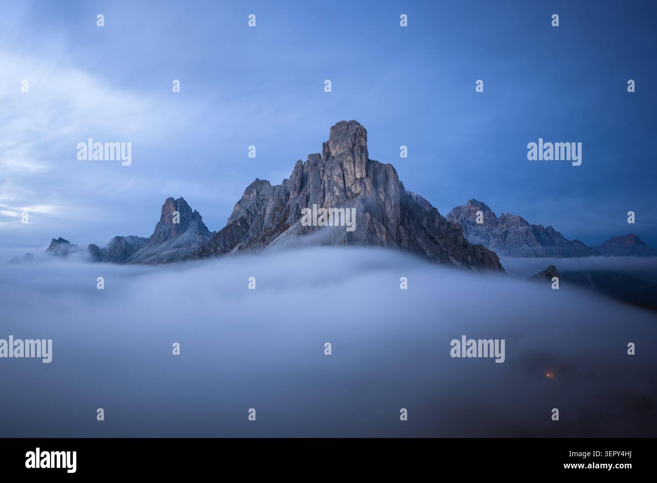 Les sommets au-dessus de Passo Giau émergent d'une mer de nuages pendant l'heure bleue dans les Dolomites. Paysage alpin atmosphérique avec brouillard Banque D'Images