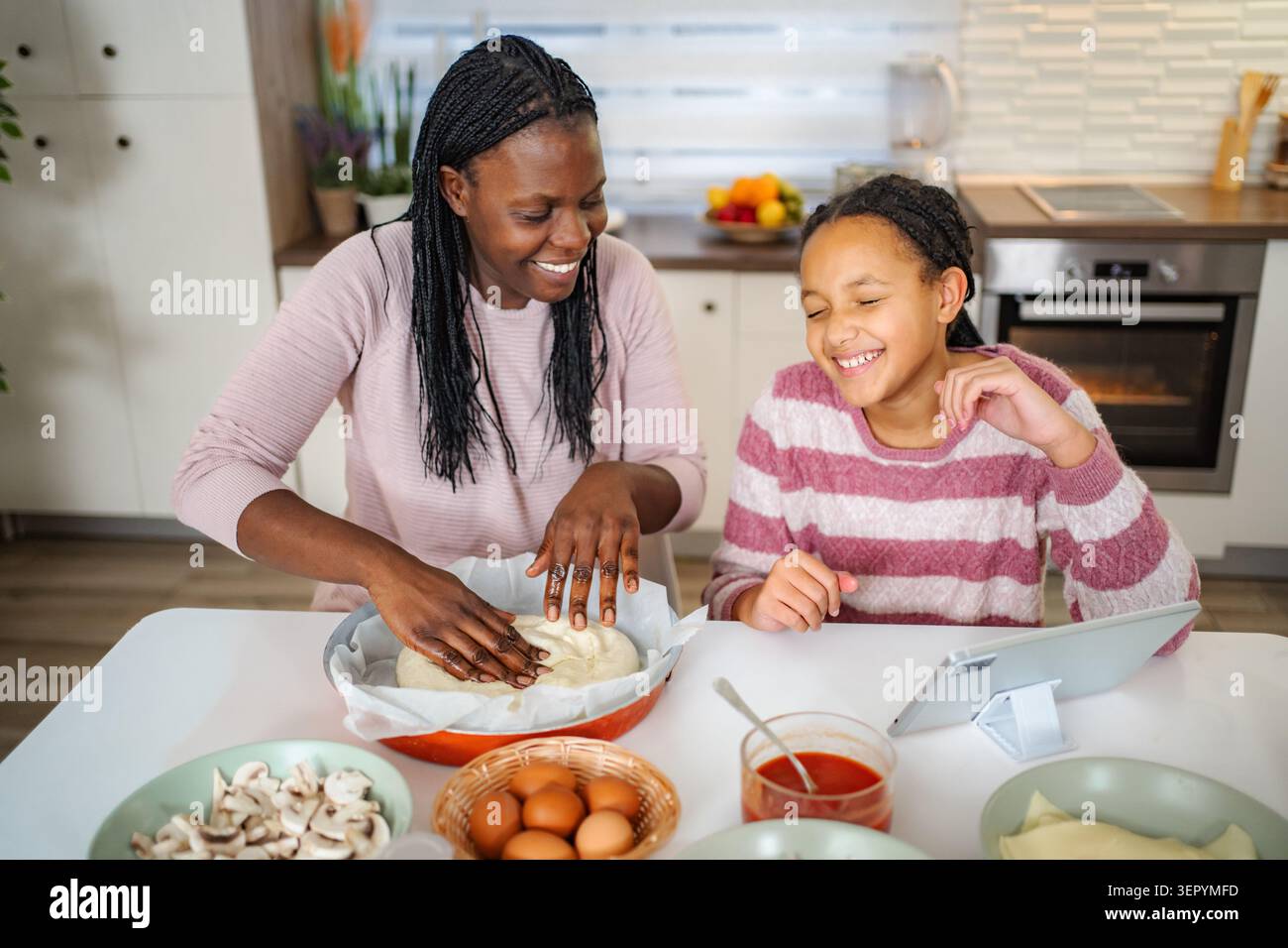 Mère et fille faisant la pizza ensemble dans la cuisine Banque D'Images