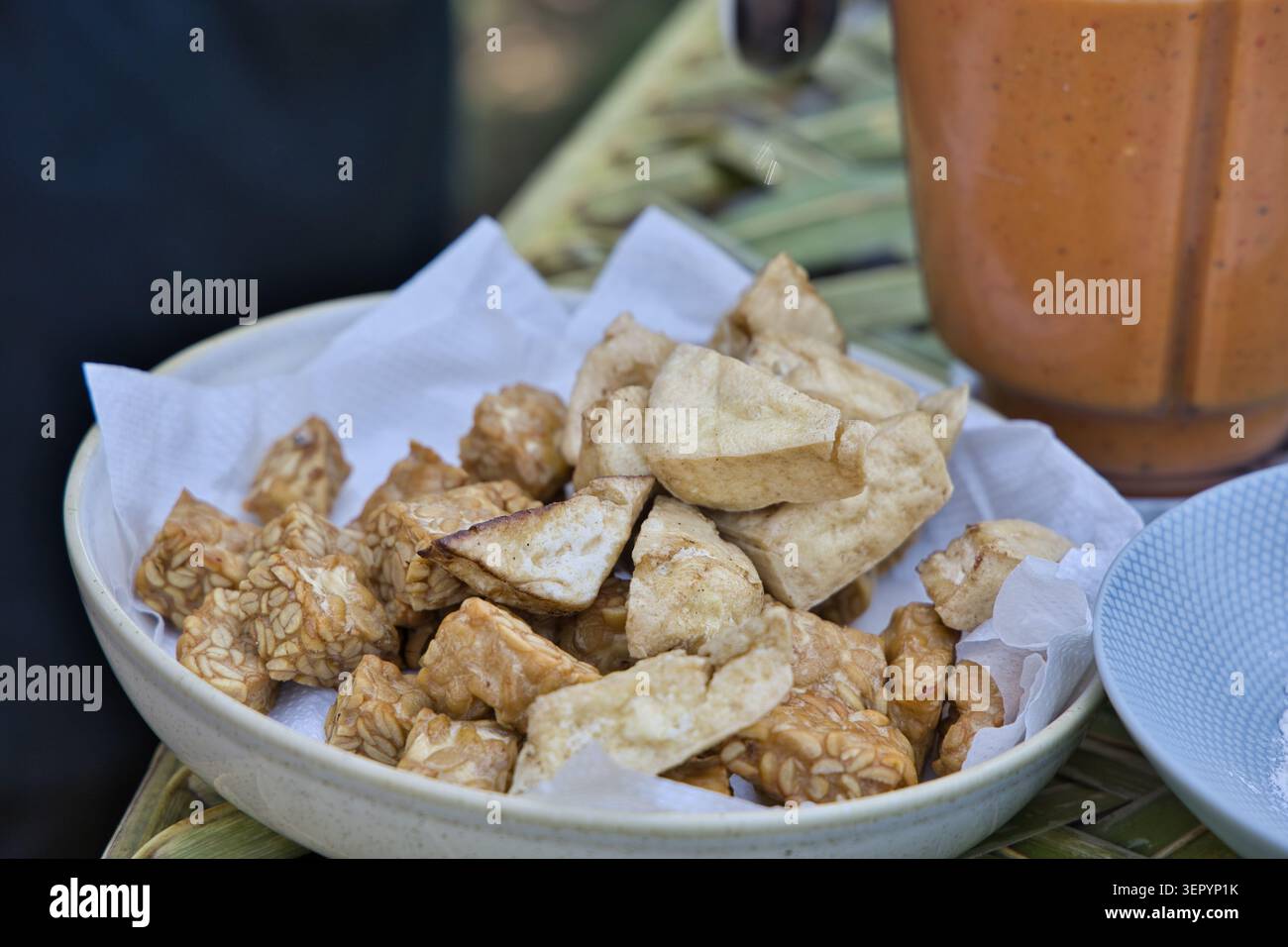 Morceaux de tempeh et de tofu frits servis dans un bol en céramique recouvert de papier, capturés lors d’un authentique cours de cuisine balinaise à Bali, en Indonésie. Banque D'Images