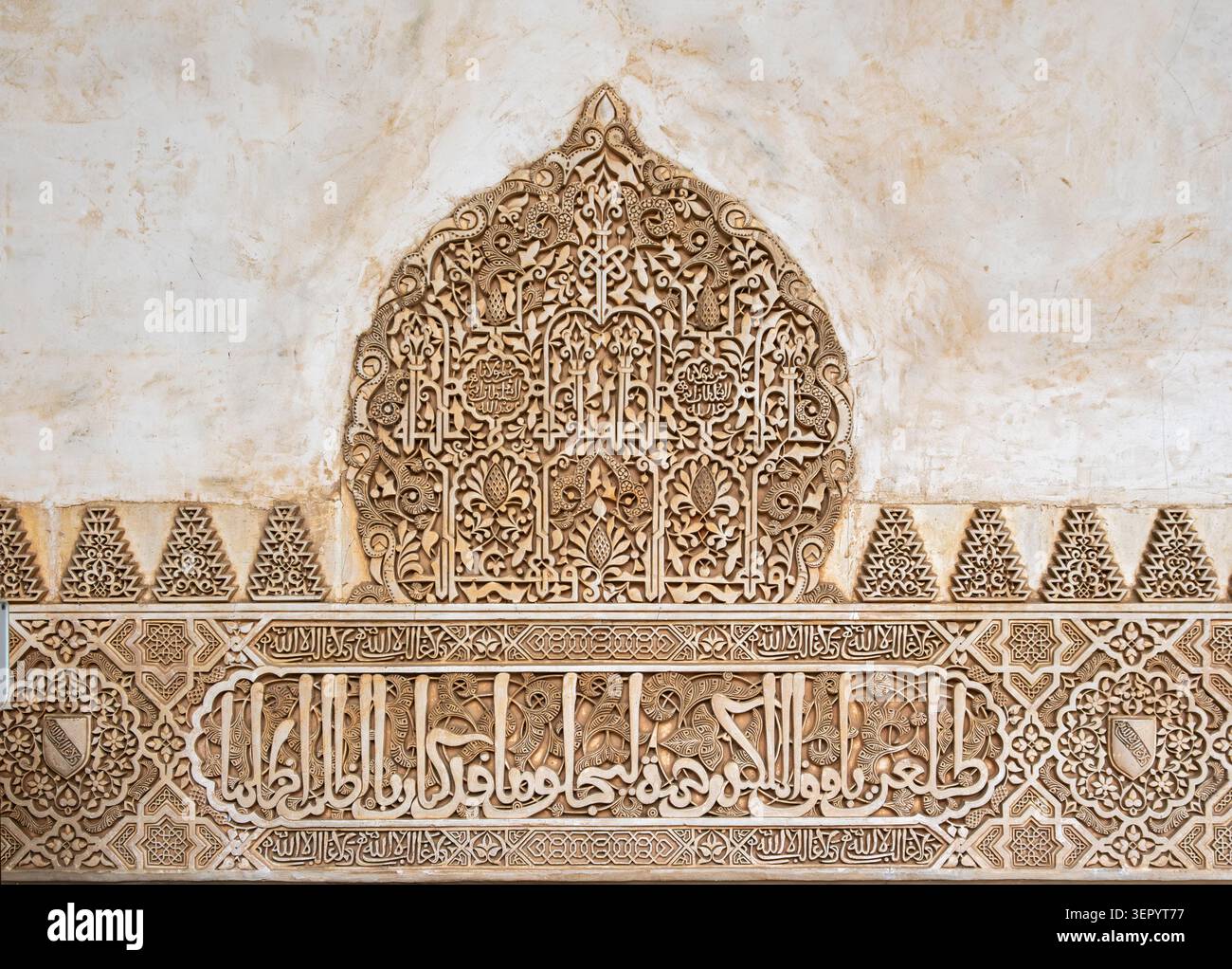 Vue détaillée de beaux motifs arabesques en stuc sculpté mauresque et d'inscriptions calligraphiques arabes sur un mur de plâtre à l'Alhambra, Espagne Banque D'Images