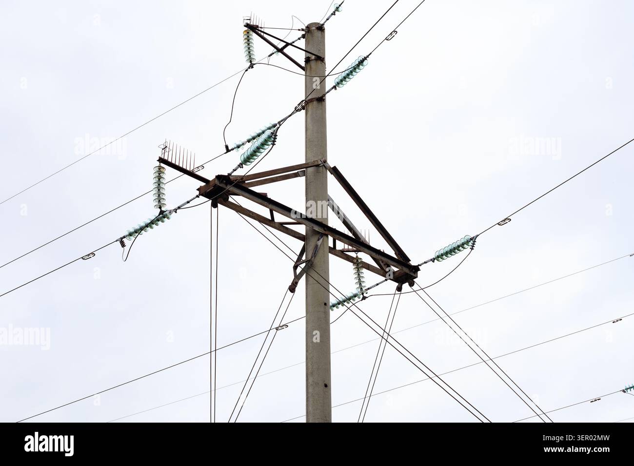 Les lignes électriques aériennes sont suspendues à un poteau en béton armé. Infrastructure de réseau de distribution électrique avec traverses métalliques et gl Banque D'Images