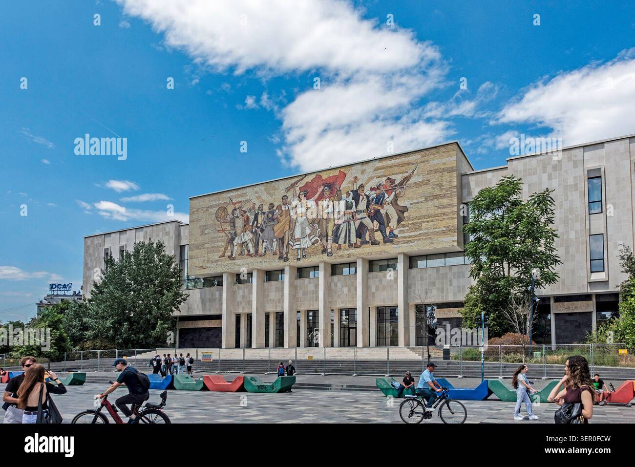 La grande façade en mosaïque du Musée historique national sous un ciel bleu sur la place Skanderbeg à Tirana, Albanie, avec des gens sur la place. Banque D'Images