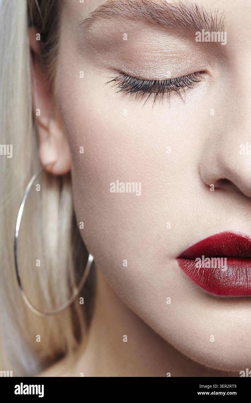 Portrait de belle jeune femme blonde avec boucles d'oreilles. Femelle blonde avec les yeux fermés Banque D'Images