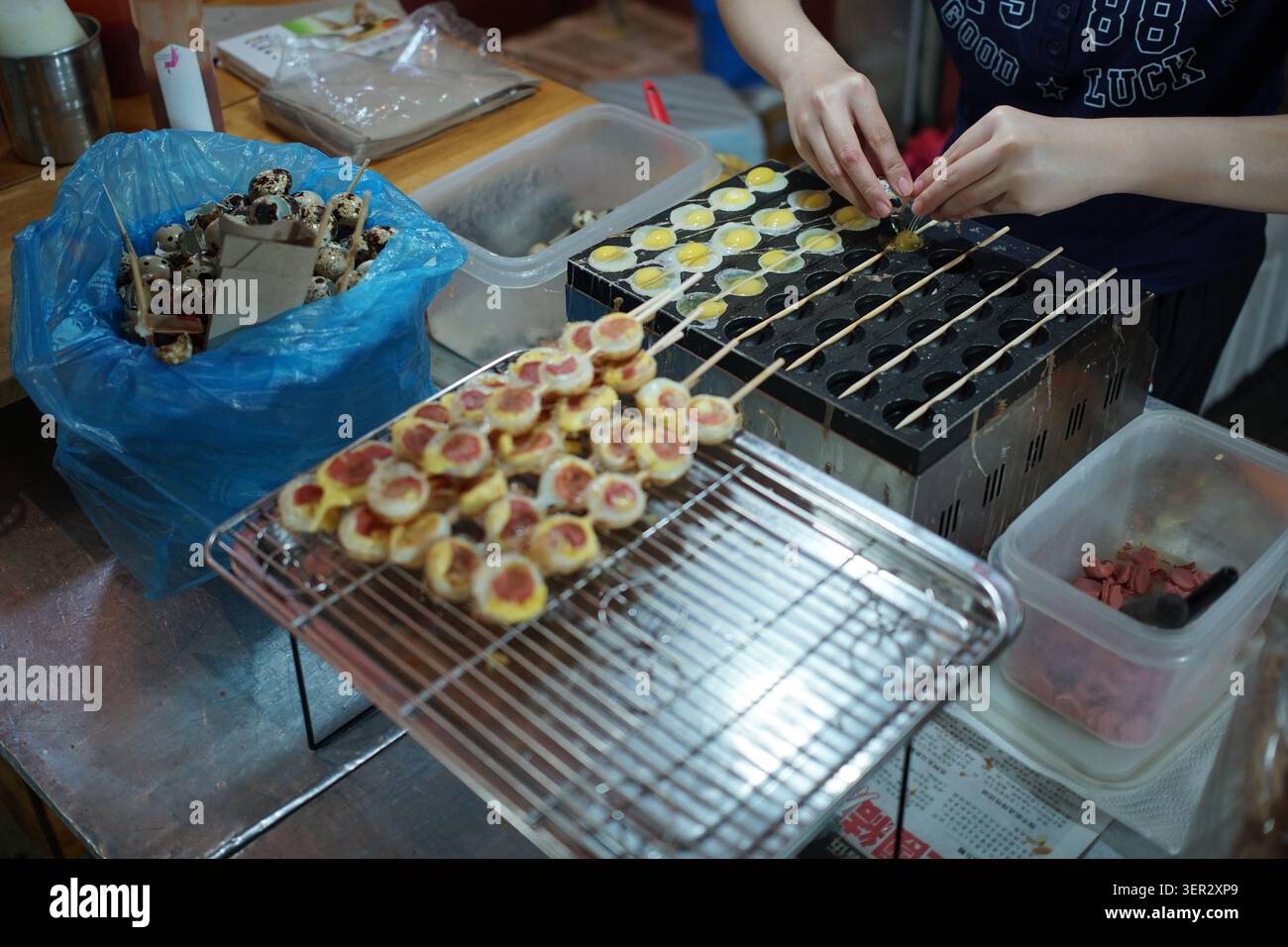 Vendeur de nourriture de rue préparant des brochettes d'œufs de caille sur une poêle de cuisson à un marché nocturne à Melaka, en Malaisie. Banque D'Images