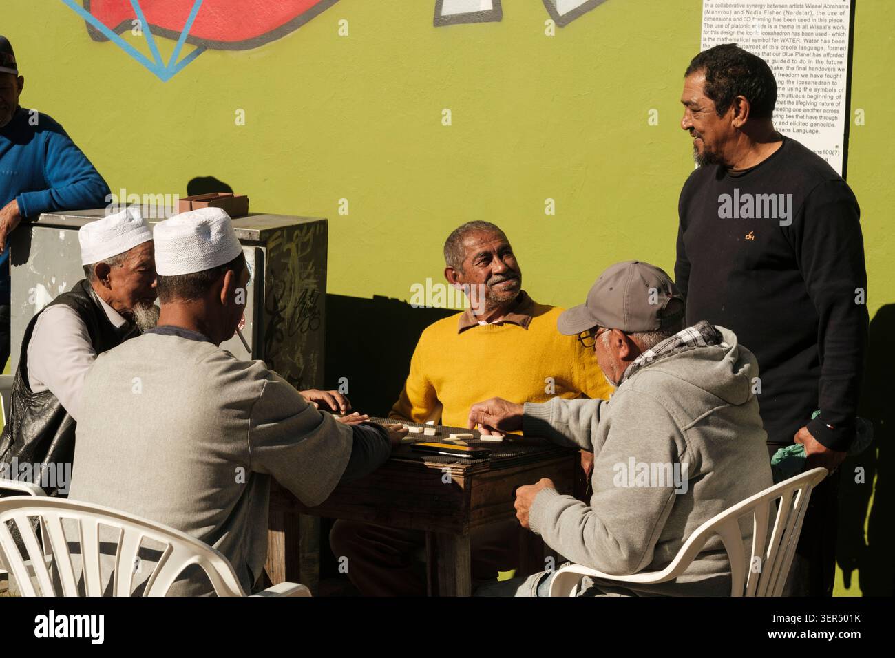 Scène de rue typique dans la destination populaire pour les voyageurs de Bo-Kaap, avec des hommes malais locaux jouant à des jeux de société dehors dans la rue l'après-midi. Banque D'Images