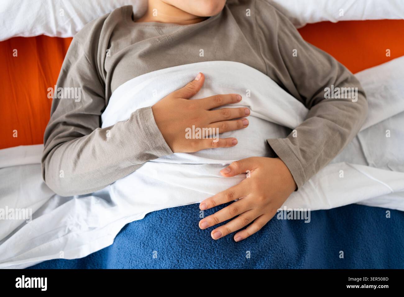 D'en haut de la récolte anonyme mâle en pyjama couché dans le lit sous une couverture chaude et dormant Banque D'Images