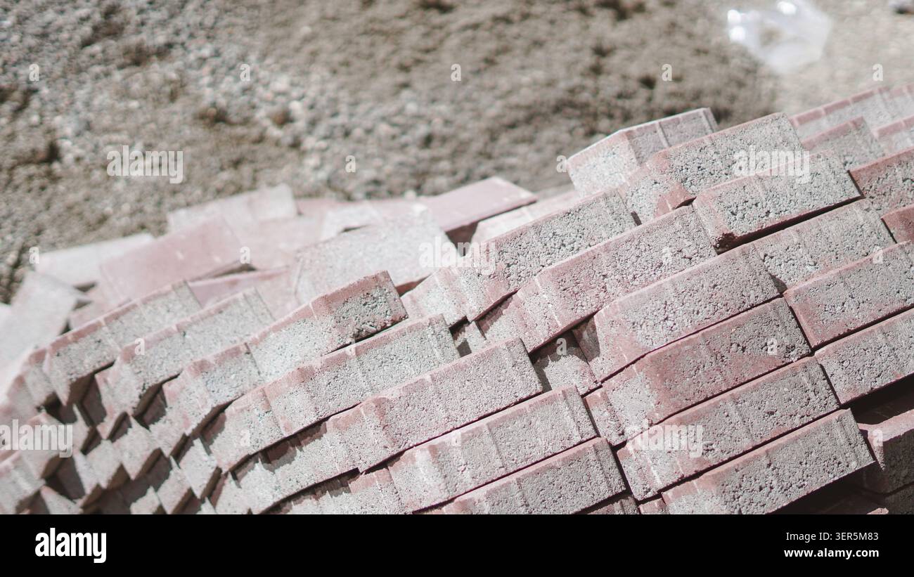 Pavés en béton rouge empilés sur le sol en gros plan. Banque D'Images