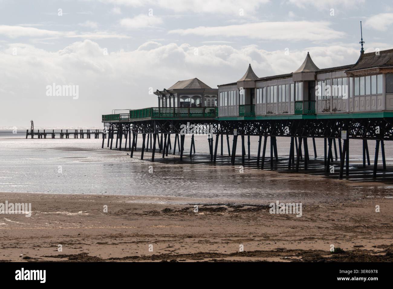 Les familles marchent le long de la plage de sable près de la jetée Lytham St Annes alors que la marée recule par une journée nuageuse en Angleterre. Banque D'Images