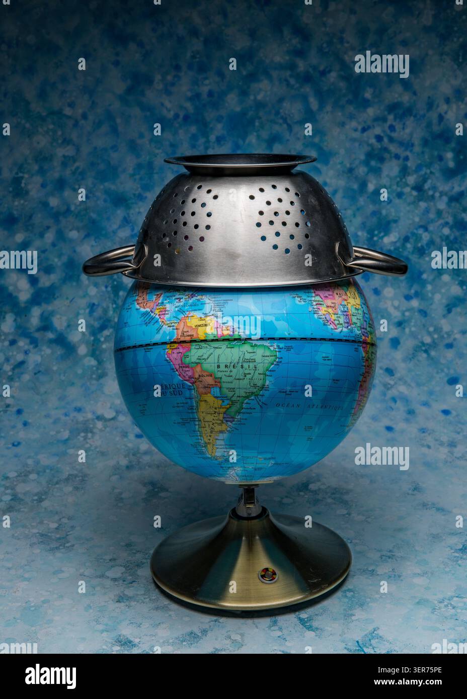 Globe avec une passoire représentant les défis mondiaux, les ressources limitées et les problèmes environnementaux critiques Banque D'Images