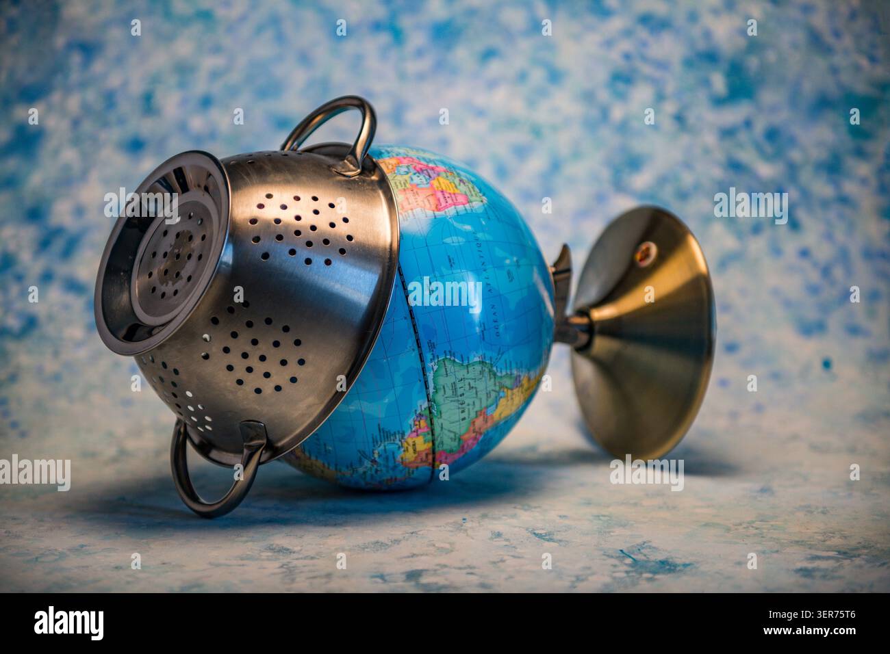 Globe drainant à travers une passoire symbolisant les menaces environnementales et la fragilité planétaire Banque D'Images