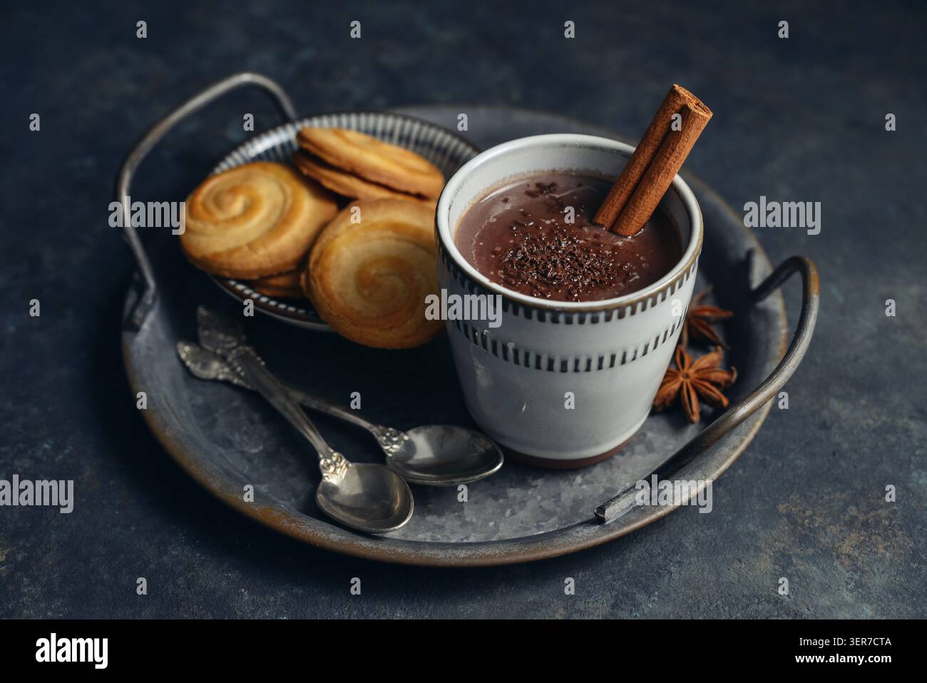 Boisson chaude traditionnelle mexicaine champurrado dans une tasse sur un plateau en métal vintage avec des biscuits, bâton de cannelle et anis étoilé sur un fond sombre. Concept Banque D'Images
