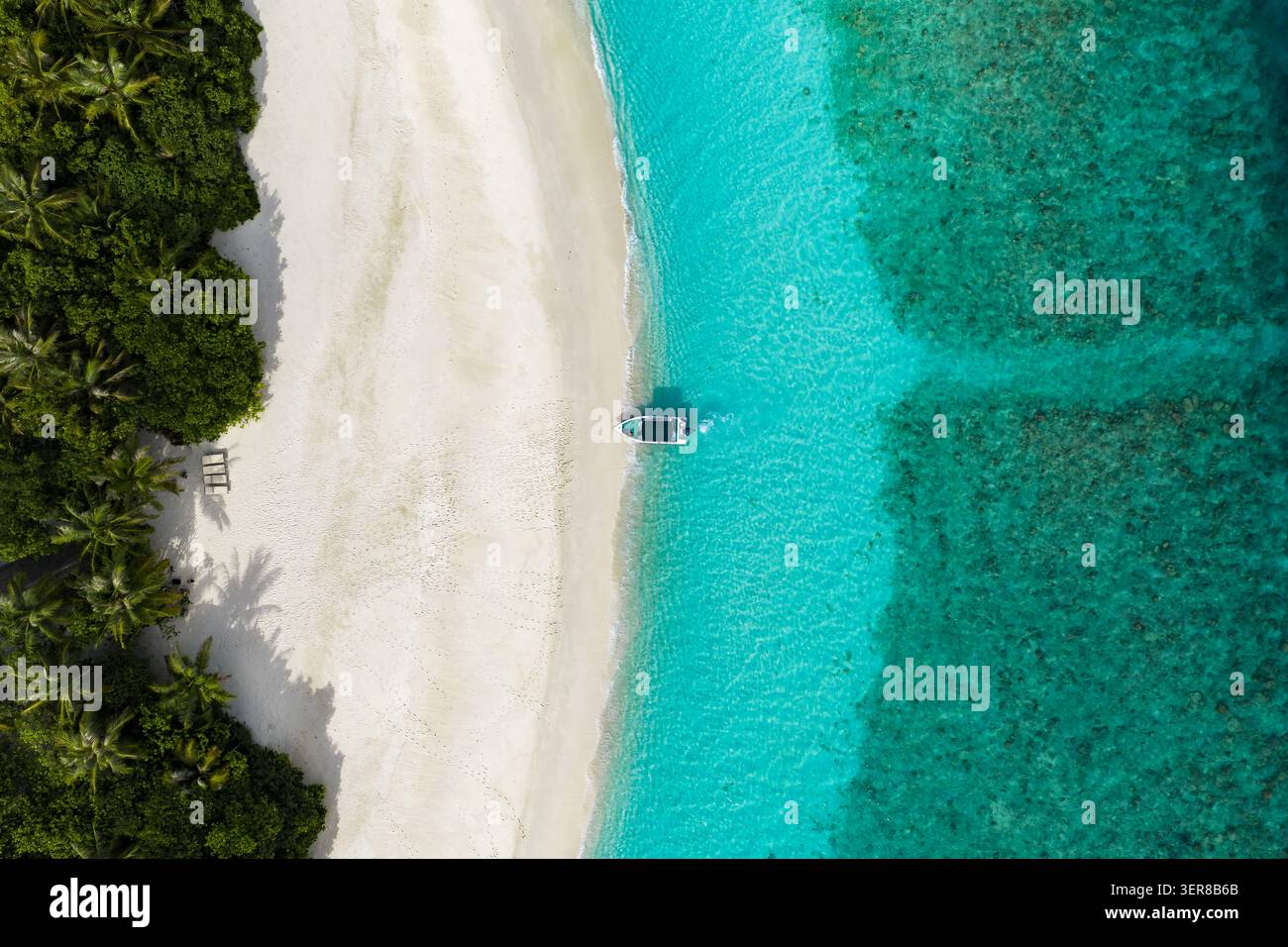 Plage aérienne maldivienne, lagon et corail avec petit bateau dérivant Banque D'Images