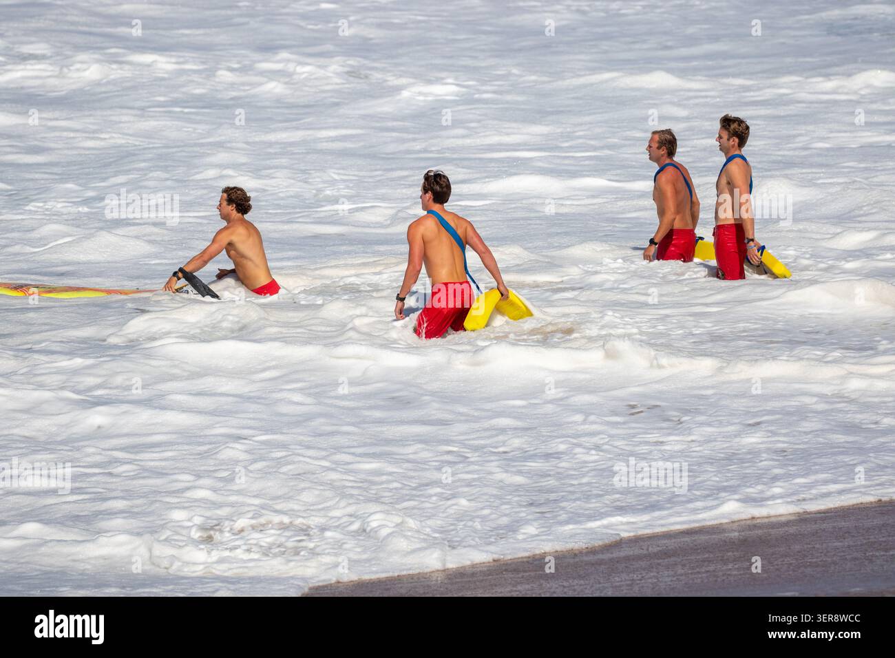 Maîtres-nageurs entrant dans l'eau pour secourir un surfeur à Newport Beach en Californie Banque D'Images