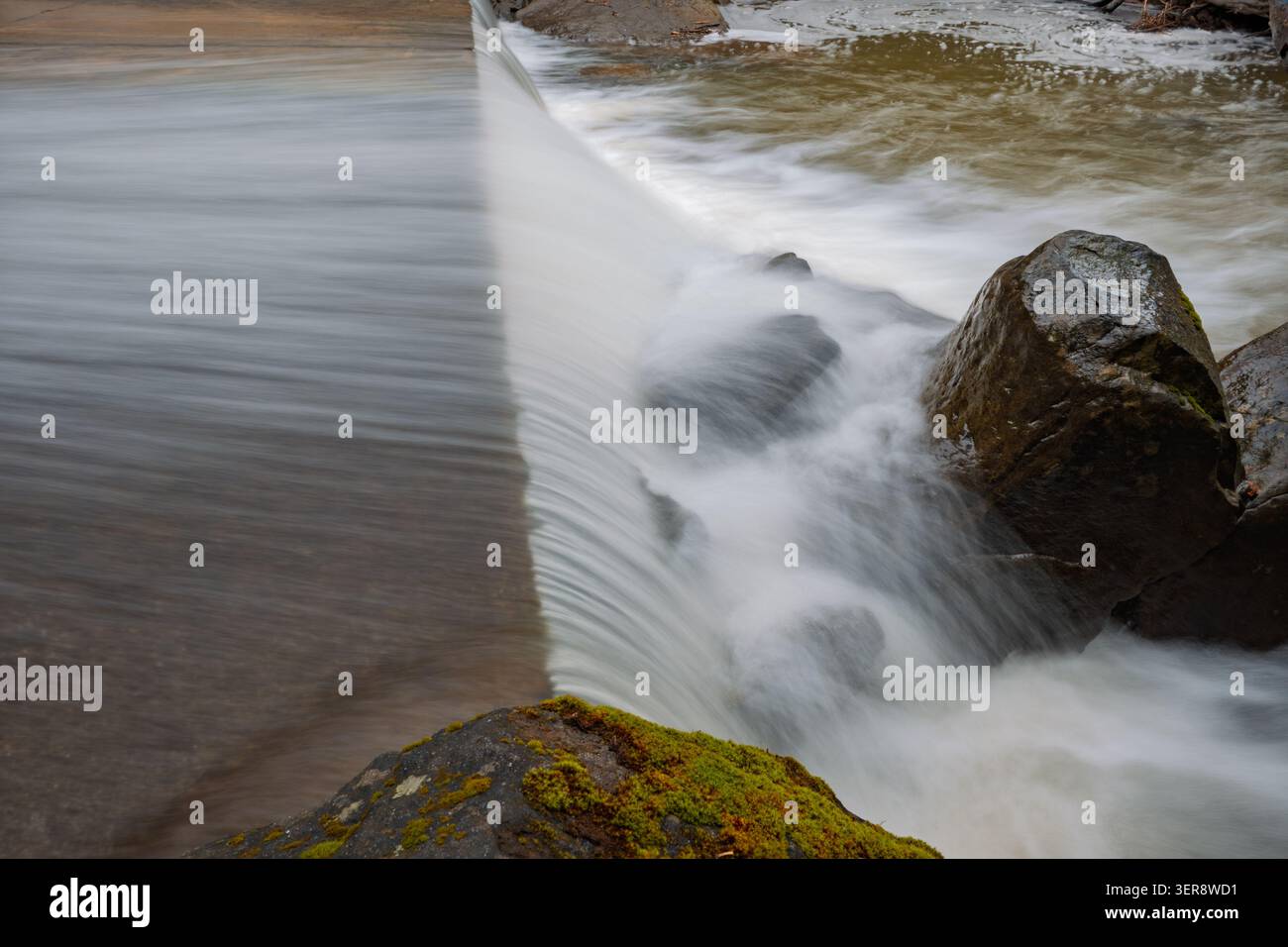 De l'eau douce et soyeuse coule sur un déversoir en béton Banque D'Images