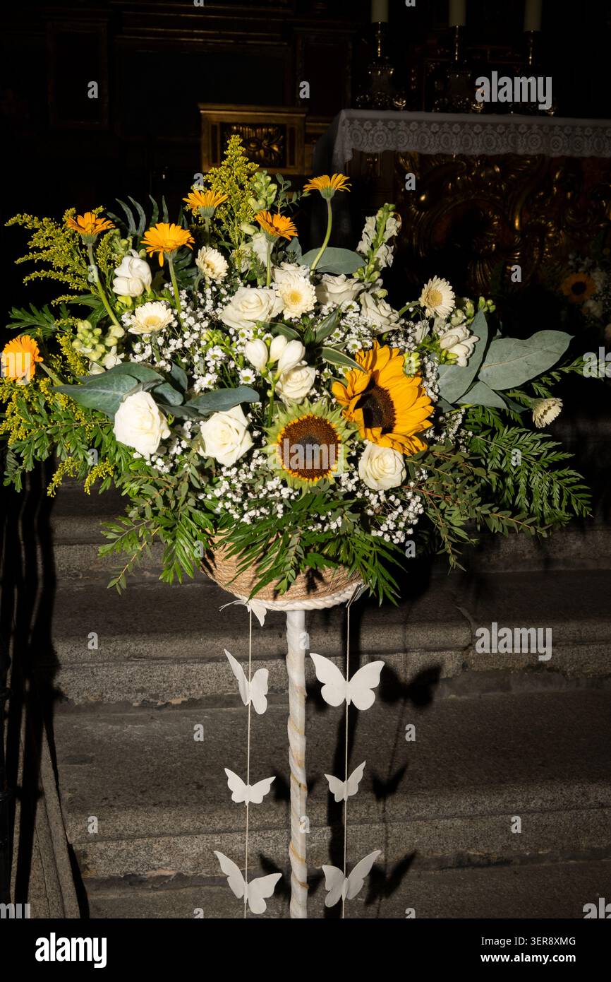 Arrangement floral décoratif avec tournesols, roses, découpes de papillons et feuillage vert dans un cadre d'église Banque D'Images