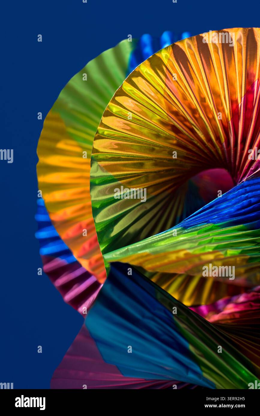 Une image abstraite vibrante avec des formes pliées et colorées créant un motif dynamique sur un fond bleu Uni. Le design met en valeur une teinte lumineuse Banque D'Images