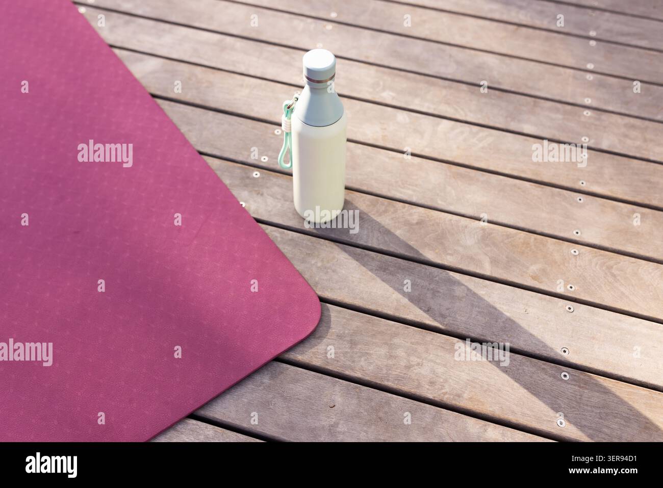 Le tapis magenta repose sur le pont en bois, la bouteille de crème jette l'ombre longue avec la sangle de menthe Banque D'Images