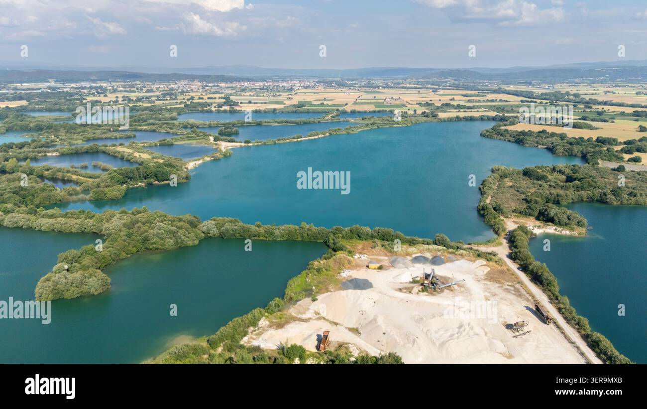 Vue aérienne montrant le site minier d'agrégats avec l'équipement de traitement, de vastes tas de sable et de nombreux lacs artificiels turquoise Banque D'Images