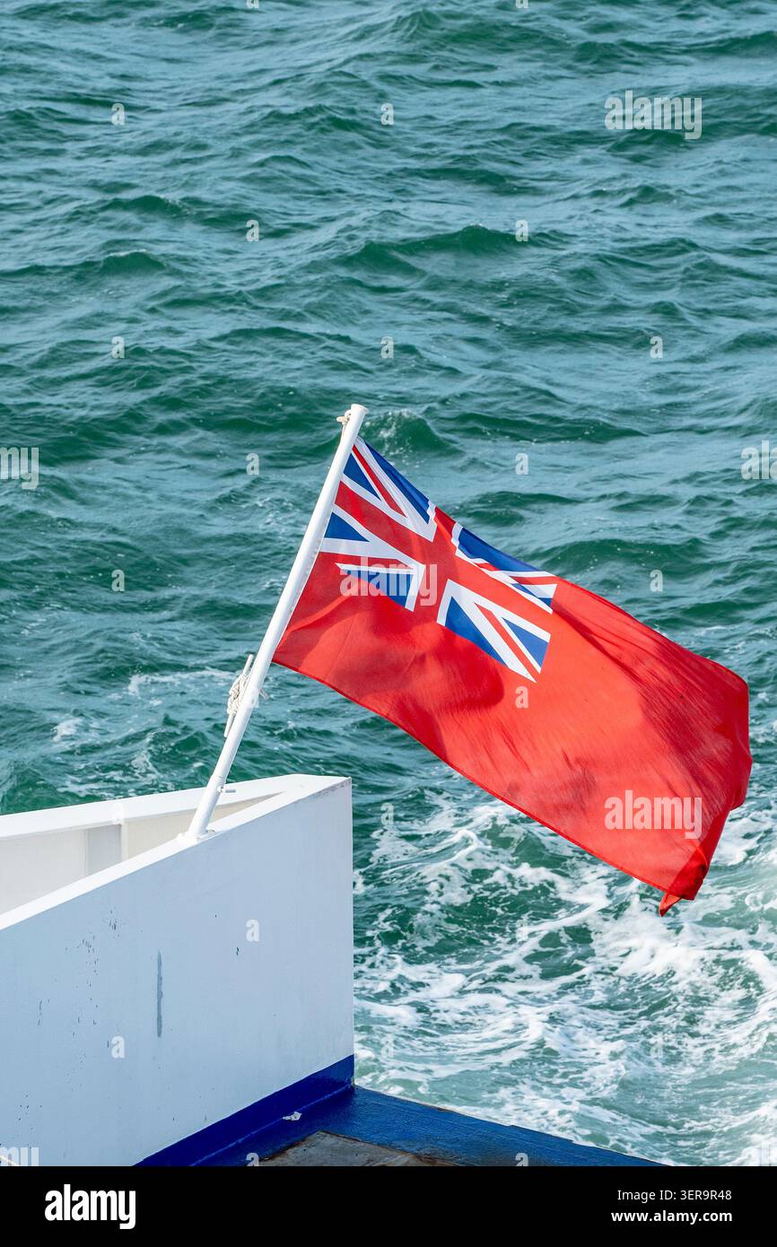 Drapeau de la marine marchande ou de la marine marchande Red Ensign volant de la poupe d'un navire en mer. Banque D'Images