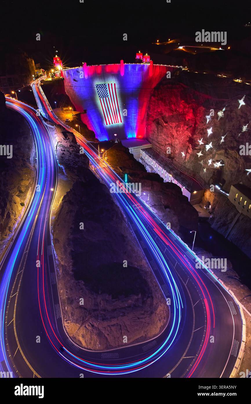 Barrage Hoover illuminé par drapeau américain et des sentiers de voiture rouge blanc bleu la nuit Banque D'Images