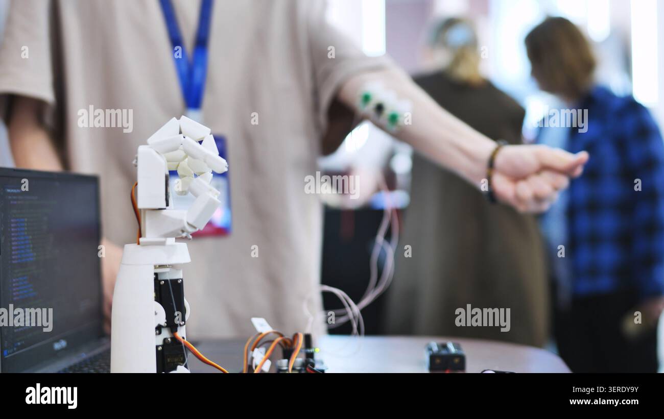 Personne testant une main robotisée bionique contrôlée par des capteurs musculaires connectés au bras Banque D'Images
