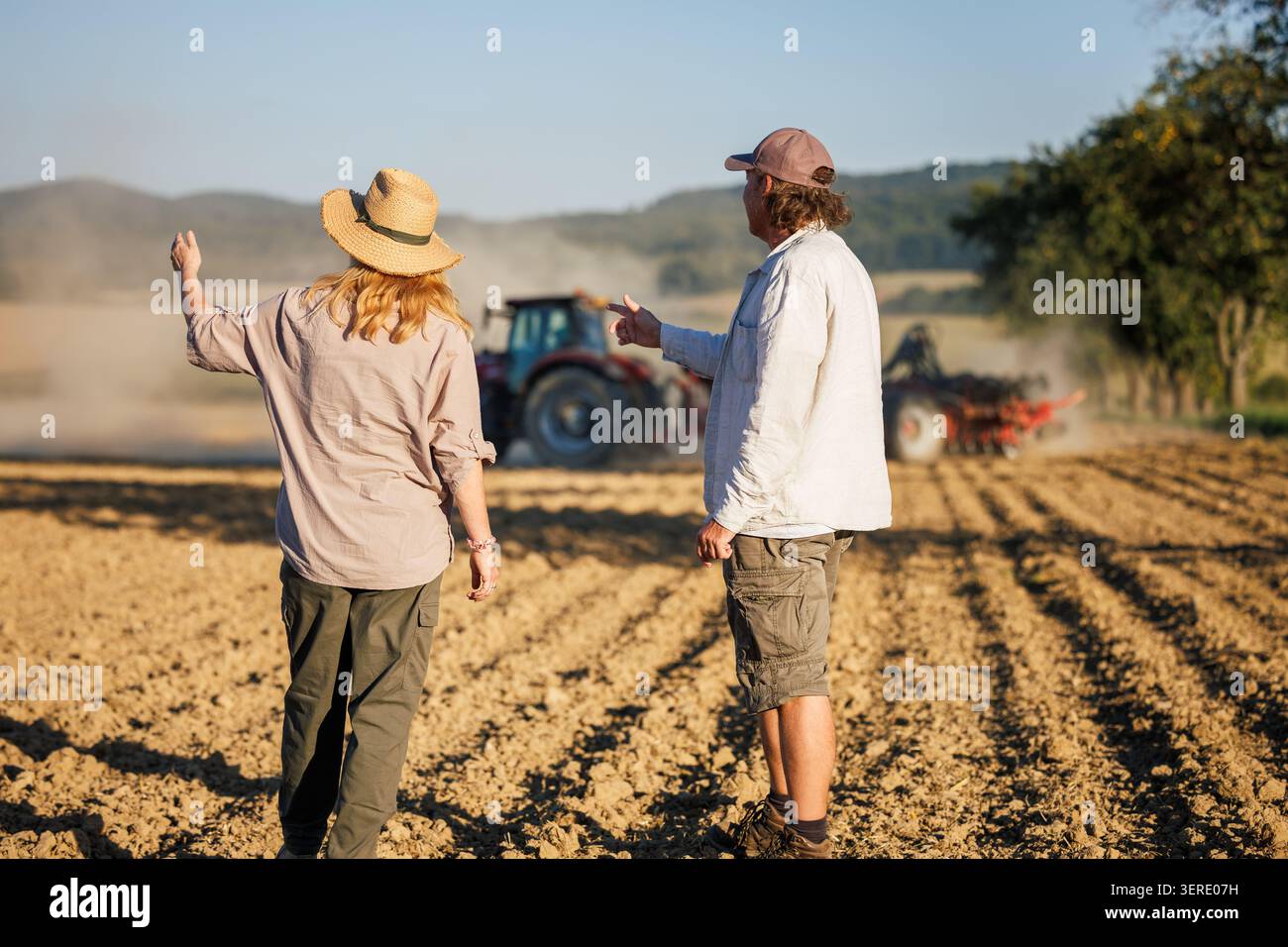 Travail d'équipe agricole. Agriculteur et agronome cherchent à semer des cultures par tracteur dans les champs cultivés à la ferme Banque D'Images