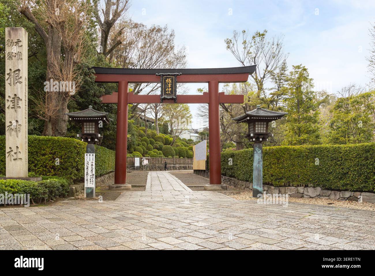 Un grand torii vermillon et un pilier de pierre marquent l'entrée principale du sanctuaire historique de Nezu à Bunkyo, Tokyo, Japon. Banque D'Images