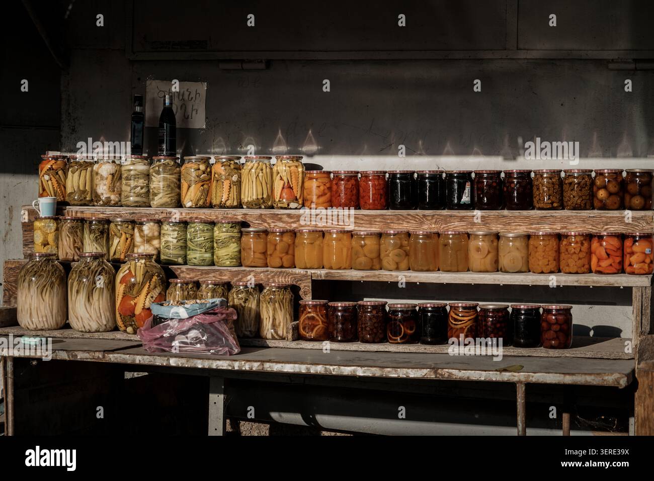 De nombreux bocaux en verre remplis d'un assortiment vibrant de légumes marinés maison et de conserves de fruits sucrés sont méticuleusement exposés sur le woo rustique Banque D'Images