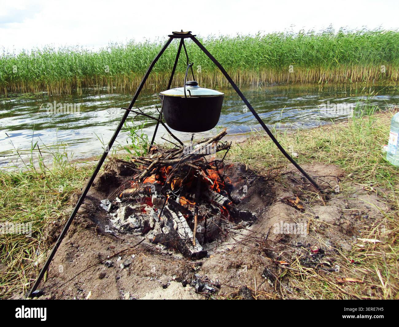 Préparation traditionnelle de la nourriture de camping sur un feu ouvert près du lac avec des roseaux. Banque D'Images