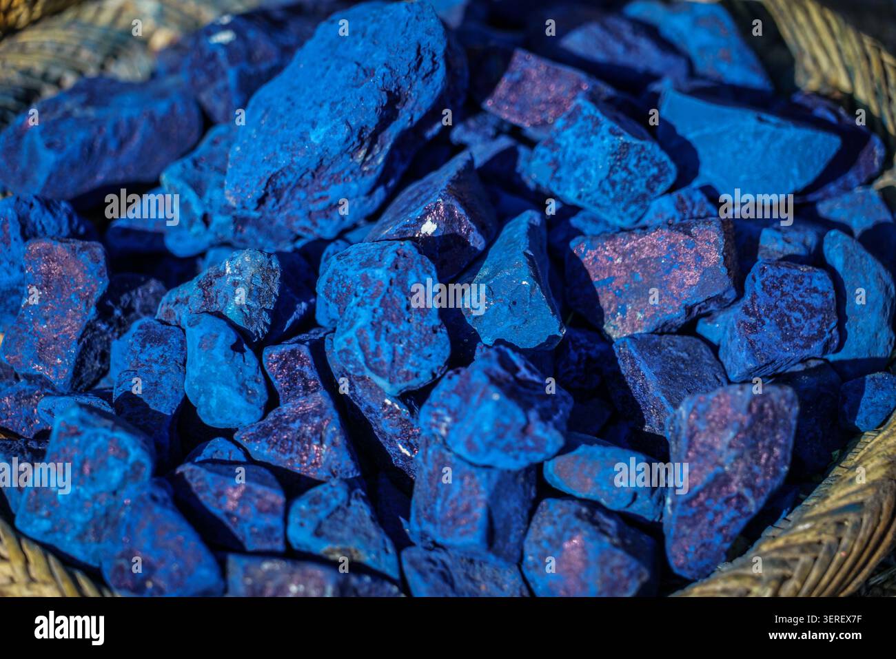 Gros plan d'un gros tas de morceaux de minéraux bleus éclatants avec des inclusions brun rougeâtre. Les pierres brutes, de forme irrégulière sont contenues Banque D'Images