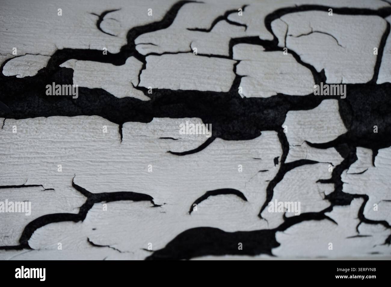 Macro texture abstraite de peinture blanche fissurée sur une surface rustique sombre Banque D'Images