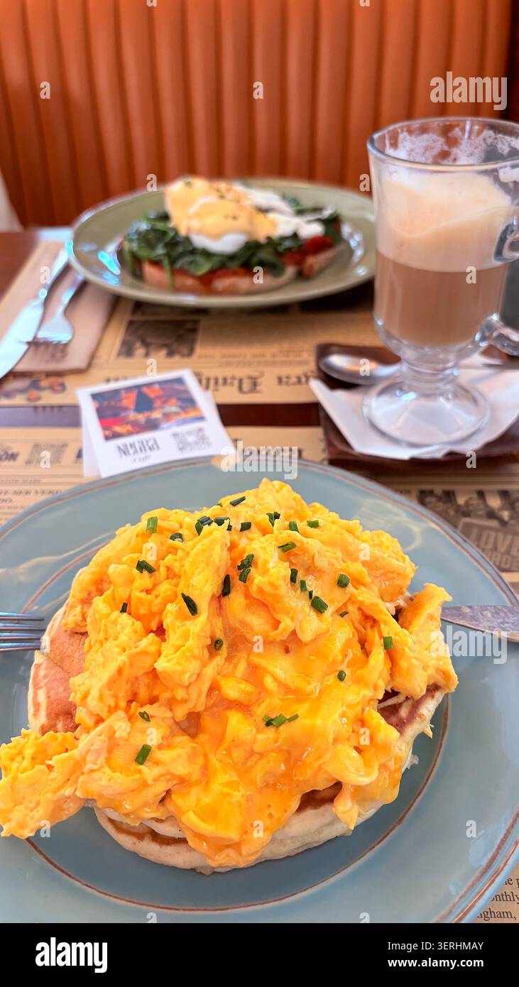 Œufs brouillés portugais traditionnels avec chorizo et pain grillé servis avec un café latte et du jus de fruits frais dans un café de Porto, au Portugal - Image de stock capturée avec un smartphone