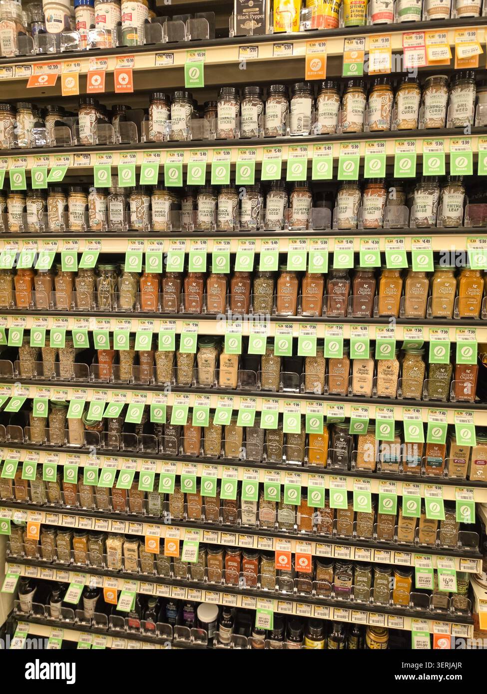 Étagères de supermarché remplies de petits emballages en verre de pousses et d'épices Simply Organic avec étiquettes/d'étiquettes de rayonnage biologiques - Image de stock capturée avec un smartphone