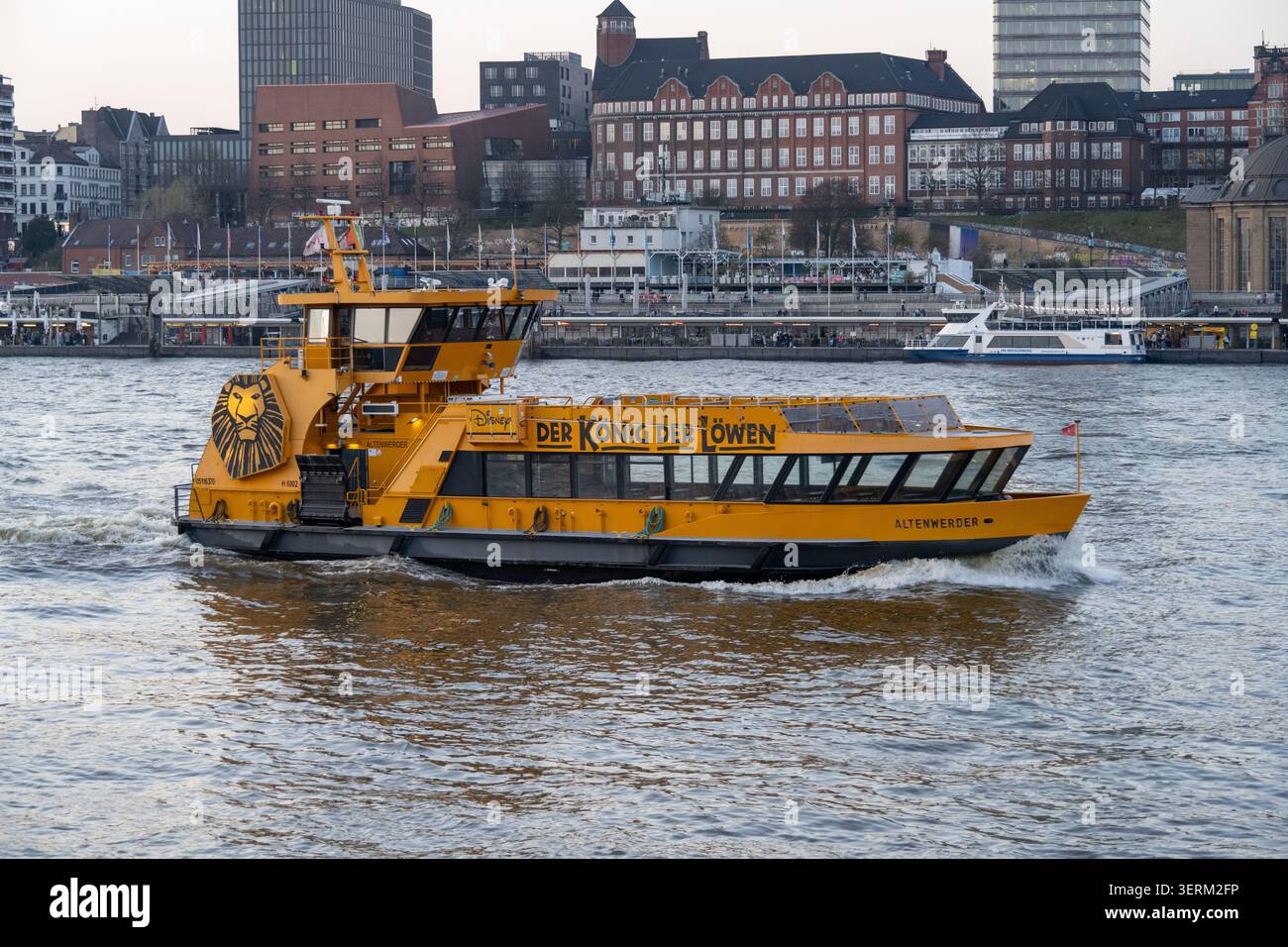 Hambourg, Allemagne - 28 février 25 : ferry de passagers jaune sur l'Elbe dans le port de Hambourg avec le front de mer de la ville en arrière-plan, Allemagne. Banque D'Images