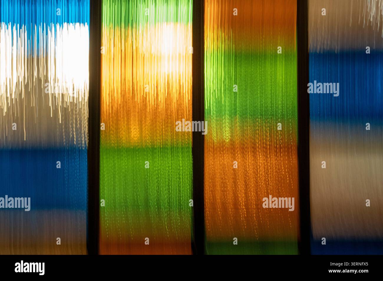 Fond abstrait vibrant utilisant ICM (Intentional Camera Movement) avec des traînées de lumière verticales en émeraude, ambre doré et céruléen. Rythmique e Banque D'Images