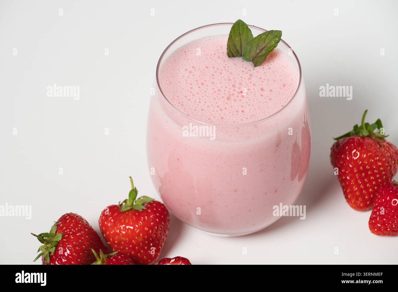 Milkshake aux fraises avec des fraises fraîches sur fond blanc Banque D'Images