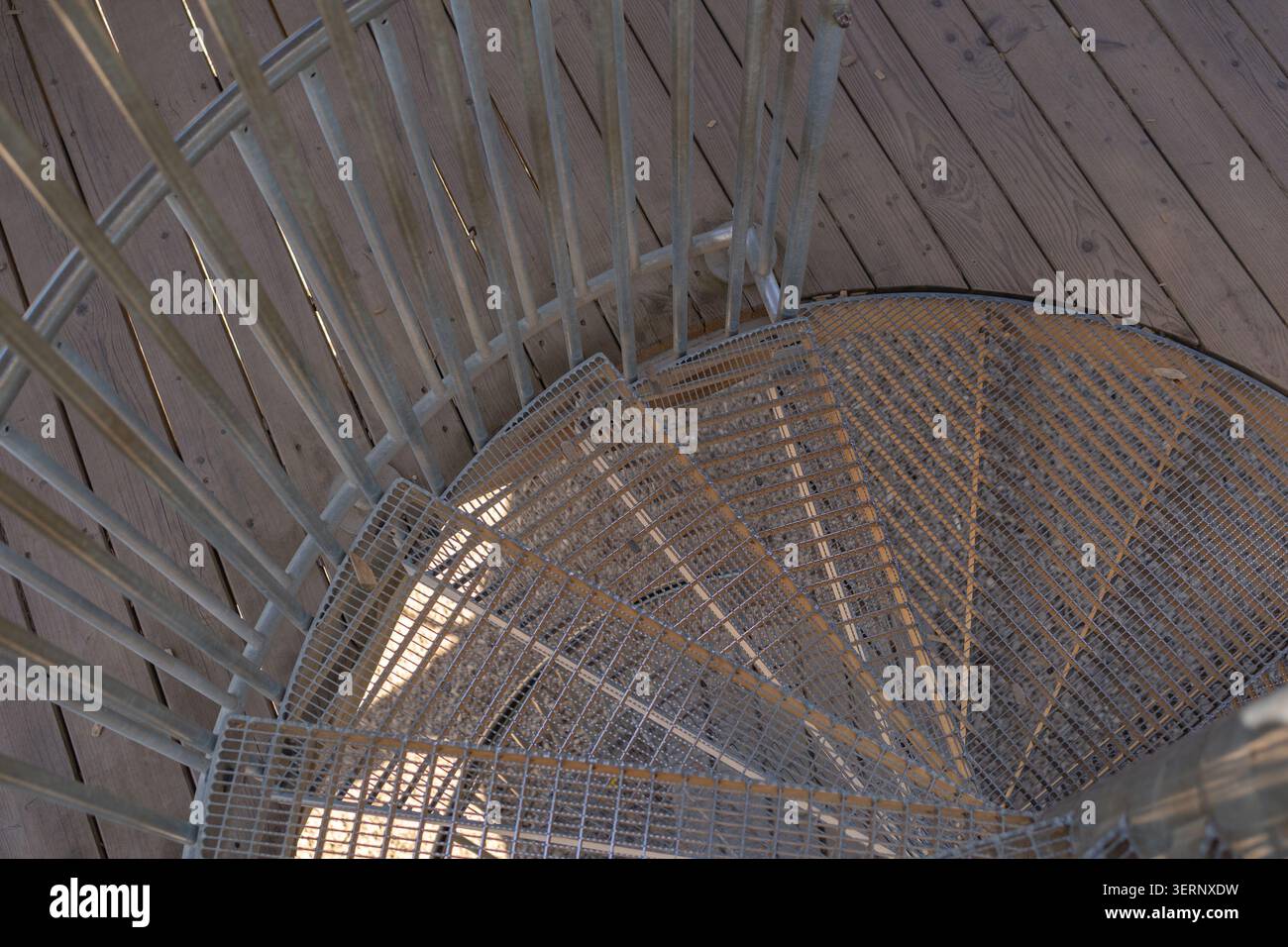 Gros plan en angle élevé regardant vers le bas du point d'entrée d'un escalier extérieur en métal en spirale avec garde-corps et plancher en bois. Détails architecturaux Banque D'Images