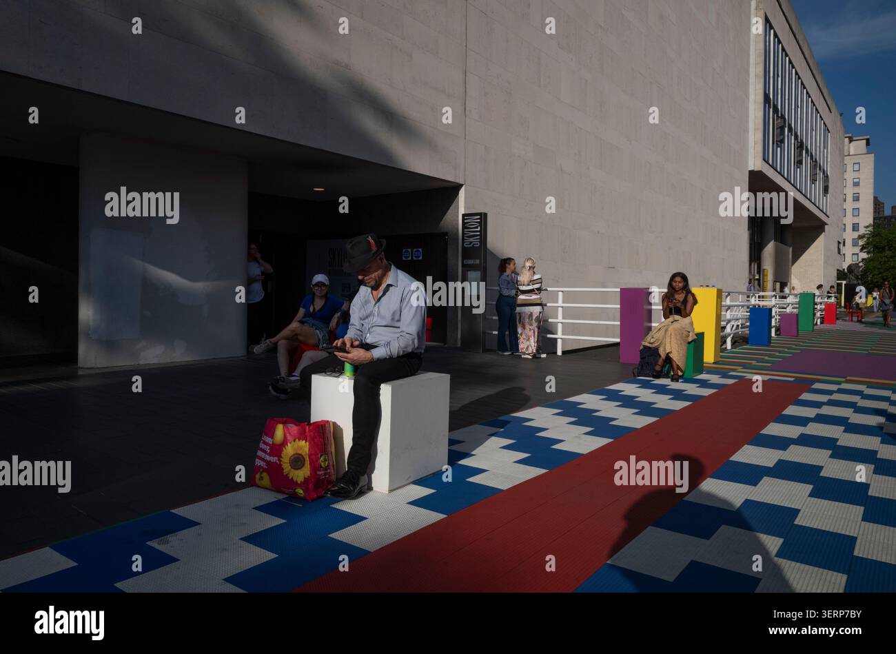 Un homme est assis sur l'un des bancs déformés situés sur la passerelle funky à l'extérieur du Royal Festival Hall sur la Southbank, Londres, Angleterre, Royaume-Uni Banque D'Images