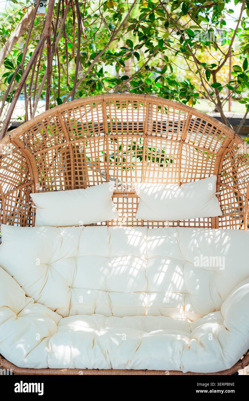 Confortable chaise suspendue en rotin dans un jardin ensoleillé Banque D'Images