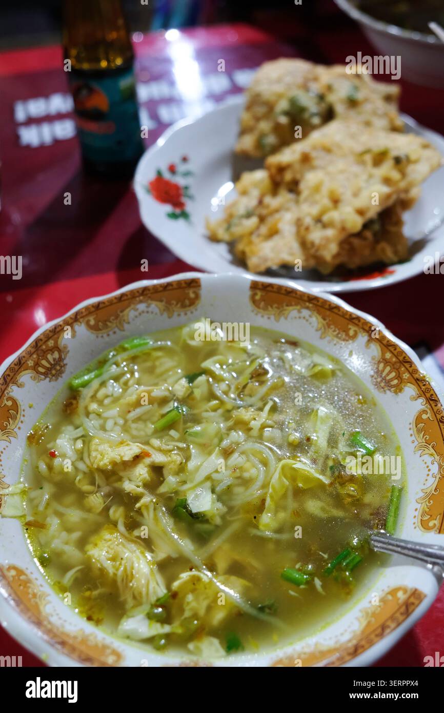 Soupe de poulet indonésienne traditionnelle ou ayam soto servi avec du riz et un côté de tempeh frit croustillant pour le petit déjeuner dans un restaurant local à Yogyakarta Banque D'Images