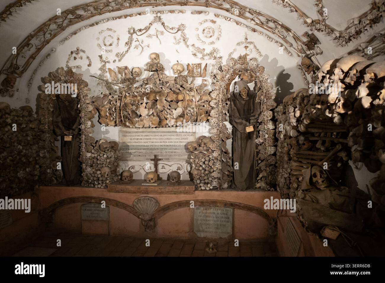 Un moine capucin squelettique vêtu de robes à capuche traditionnelles debout dans la chapelle en os ornée de la crypte capucine à Rome, en Italie. Banque D'Images