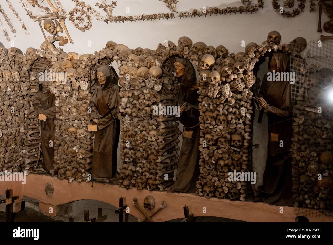 Un moine capucin squelettique vêtu de robes à capuche traditionnelles debout dans la chapelle en os ornée de la crypte capucine à Rome, en Italie. Banque D'Images